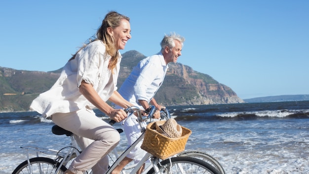 Foto sorridere delle coppie che guidano le loro bici sulla spiaggia