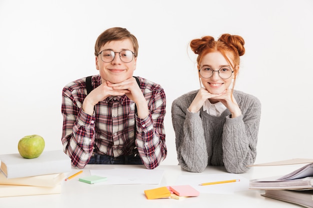 Smiling couple of school nerds sitting at the desk