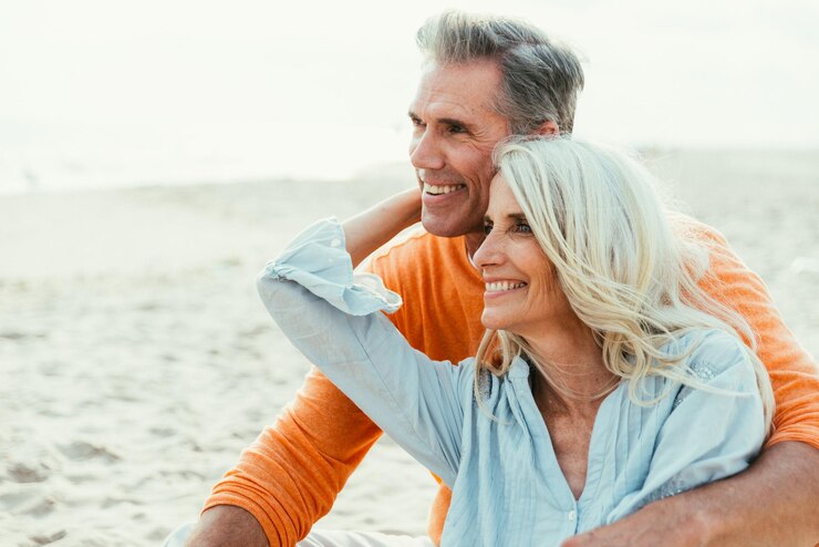 Smiling couple sitting at sandy beach