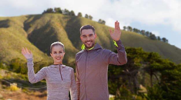 Photo smiling couple in sport clothes waving hand