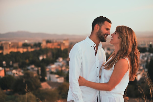 smiling couple standing against cityscape during sunset