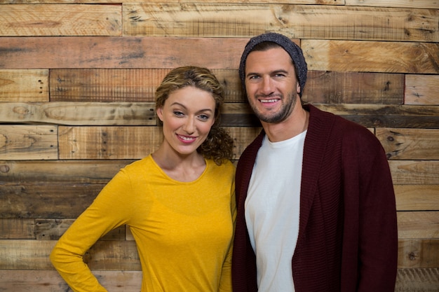 Smiling couple standing against wooden wall in coffee