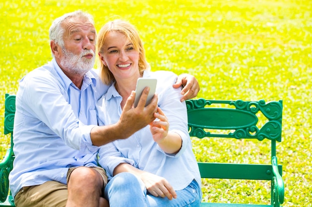 Smiling couple taking selfie while sitting on bench at park