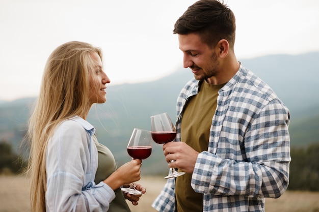 Smiling couple toasting wine glasses outdoors in mountains