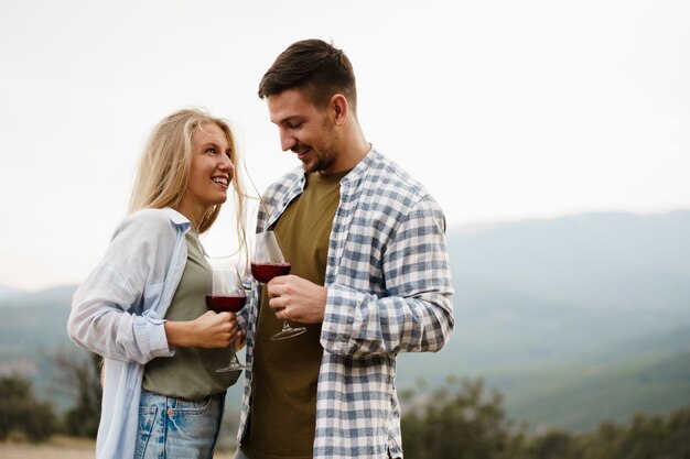 Smiling couple toasting wine glasses outdoors in mountains