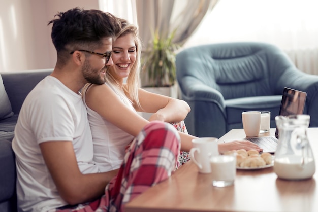 Smiling couple using laptop at home