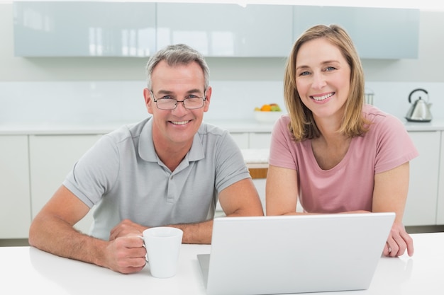 Smiling couple using laptop in kitchen