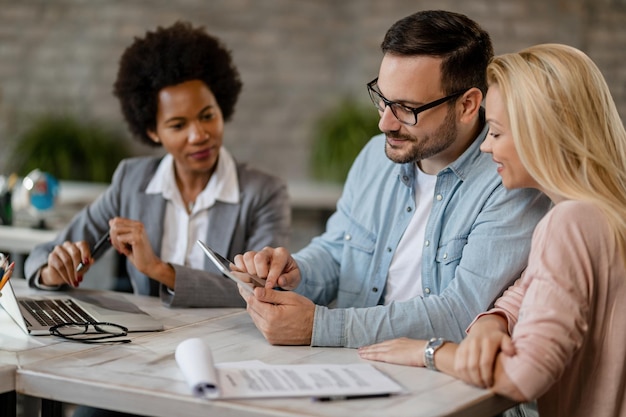 Photo smiling couple using touchpad while having a meeting with their financial advisor in the office