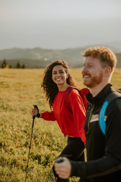 Smiling couple walking with backpacks over green hills