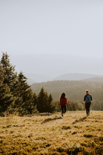 Smiling couple walking with backpacks over green hills