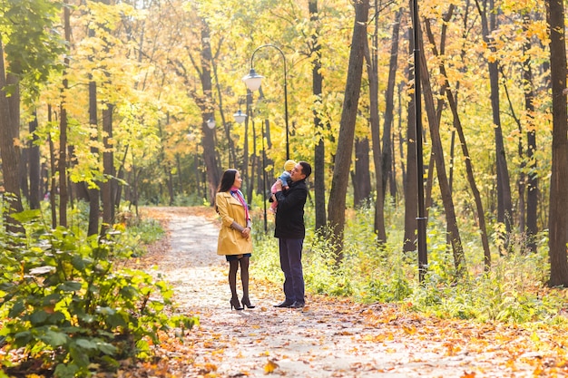 Smiling couple with baby in autumn park