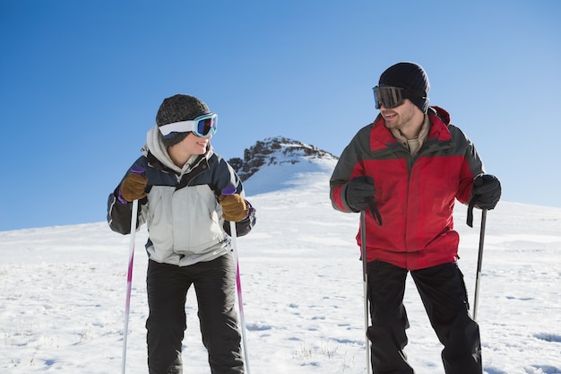 Smiling couple with ski poles on snow