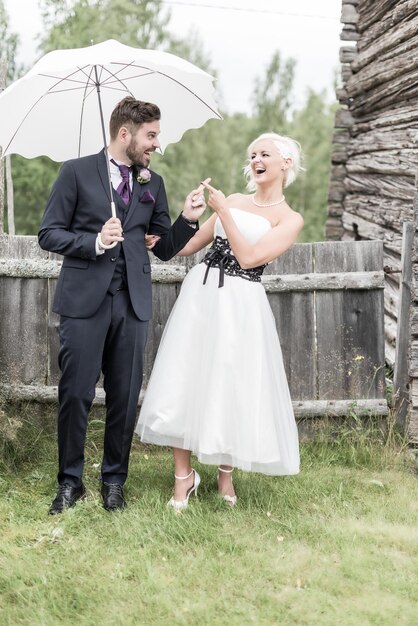 Photo smiling couple with umbrella standing on lawn