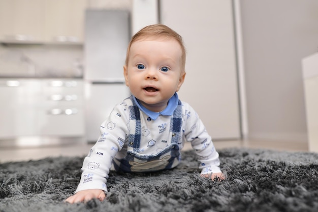 写真 じゅうたんの上で家で這う赤ちゃんの笑顔笑顔生まれたばかりの赤ちゃんの学習が這うことを開始します