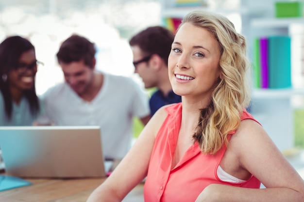 Smiling creative businesswoman working with co-workers