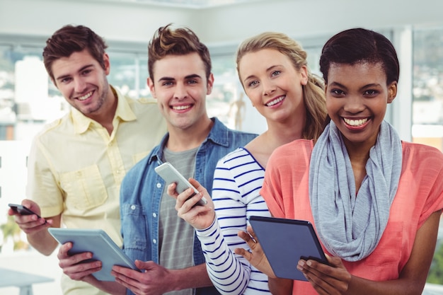 Smiling creative team standing in a line using technology