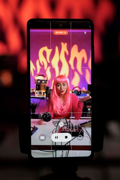 Photo smiling creator filming vlog using smartphone camera discussing lifestyle advice with subscribers, posting content on her channel. asian vlogger standing in broadcast studio recording podcast