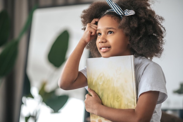 A smiling curly-haired girl with a book in hands