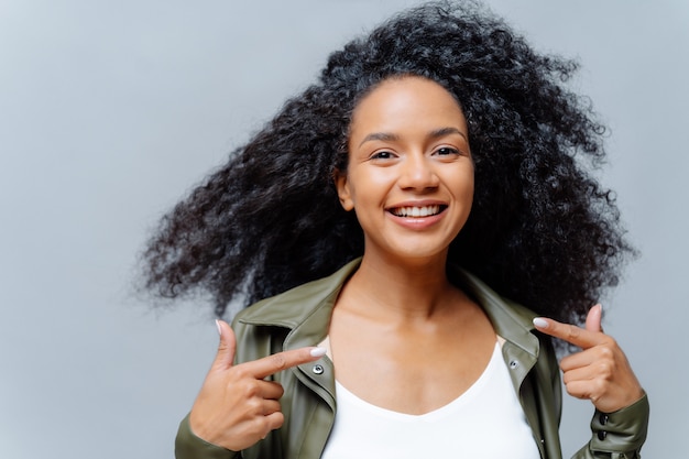 Smiling curly woman with luminous hair and casual clothing