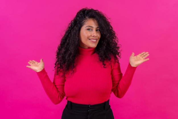 Smiling curlyhaired woman posing on a pink background studio shot lifestyle