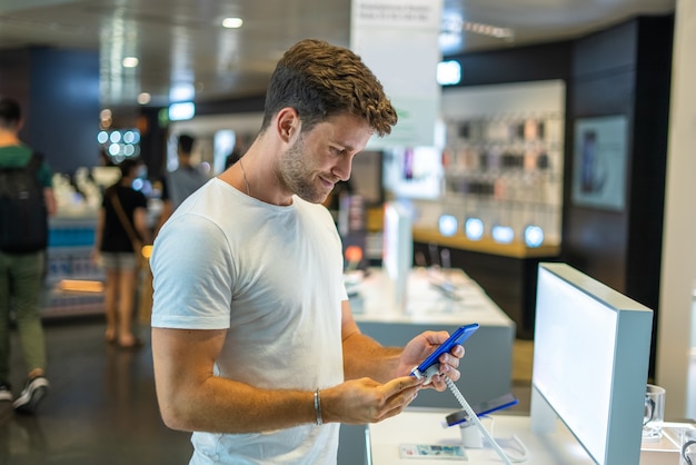 Улыбающийся покупатель тестирует смартфон в магазине