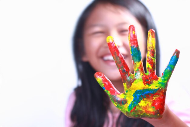 Smiling cute Asian girl showing her painted palm over white background Focus on hand