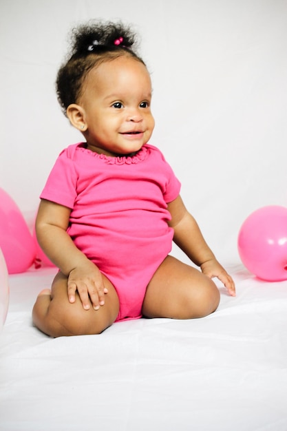 Smiling cute baby girl sitting on bed at home