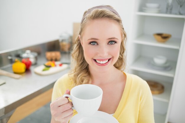 Photo smiling cute blonde holding a cup