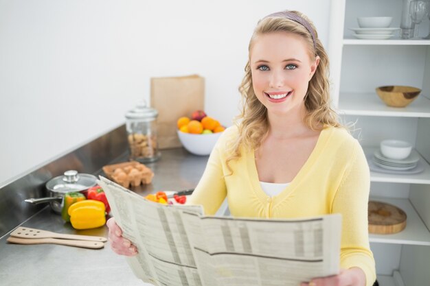 Smiling cute blonde holding newspaper