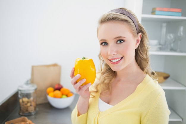 Smiling cute blonde holding a yellow pepper