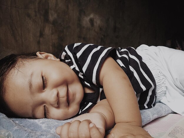 Photo smiling cute boy sleeping on bed