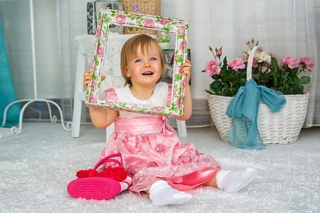 写真 笑顔の可愛い女の子が家で花のフレームを握っている