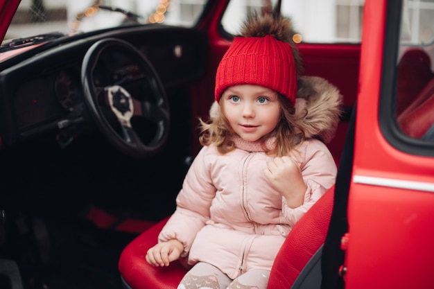 Smiling cute girl in red hat sitting in a car