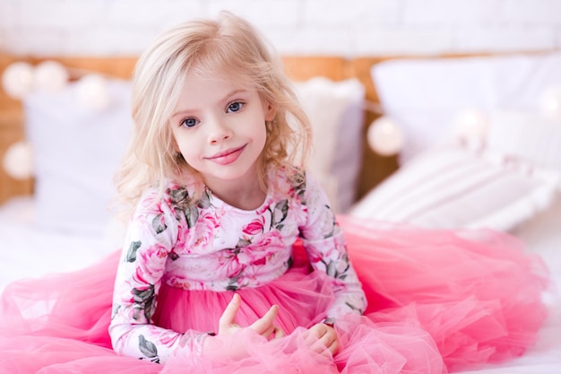 Photo smiling cute girl sitting on bed at home