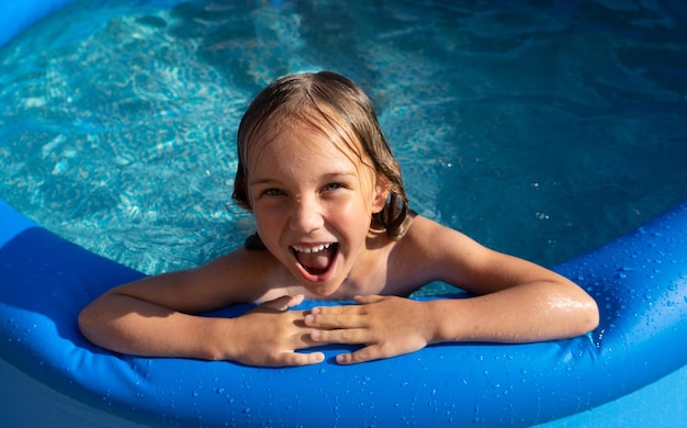 Smiling cute little girl in pool in sunny day