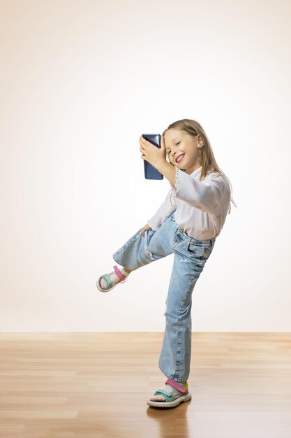 Smiling cute nice little girl dancing and looking at the phone Kids lifestyle child and modern tehcnologies