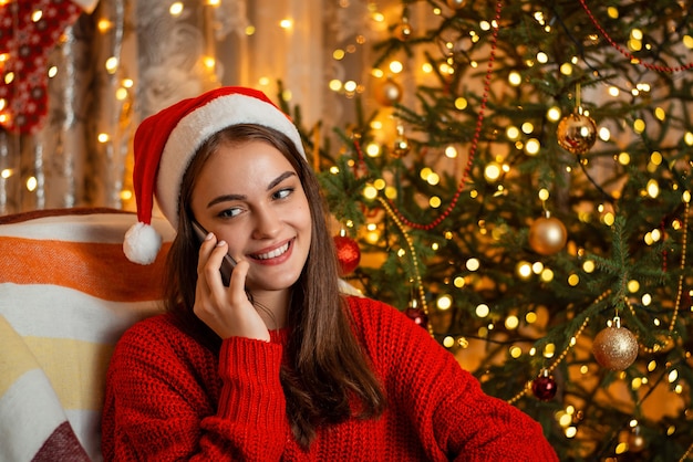 Smiling cute young girl sitting in the armchair and talking over the phone