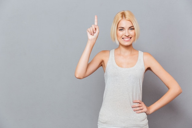 Sorridente giovane donna carina che punta verso l'alto