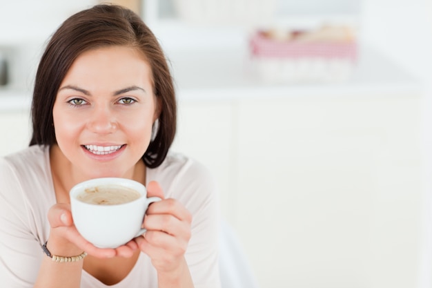 Smiling dark-haired woman having a coffee