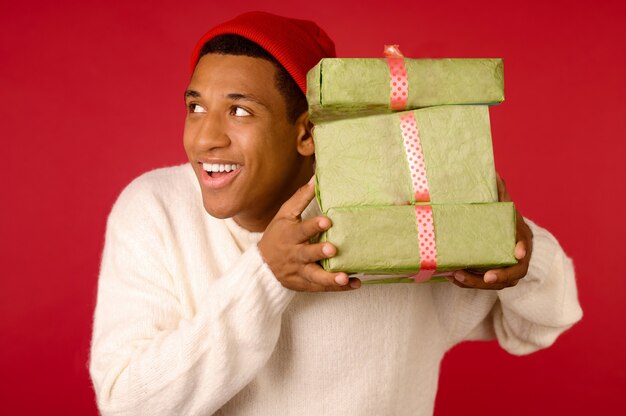 Smiling dark-skinned young guy with gift boxes in hands