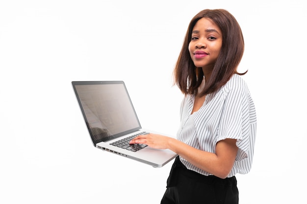 Smiling dark skinned young woman present smth on the laptop isolated