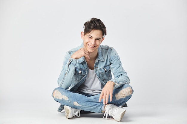 smiling darkhaired guy dressed in a white tshirt jeans and a denim jacket