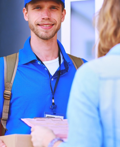 Smiling delivery man in blue uniform delivering parcel box to recipient courier service concept smil