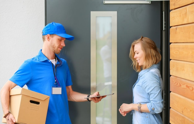 Smiling delivery man in blue uniform delivering parcel box to recipient courier service concept Smiling delivery man in blue uniform