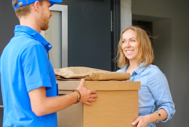 Smiling delivery man in blue uniform delivering parcel box to recipient courier service concept Smiling delivery man in blue uniform