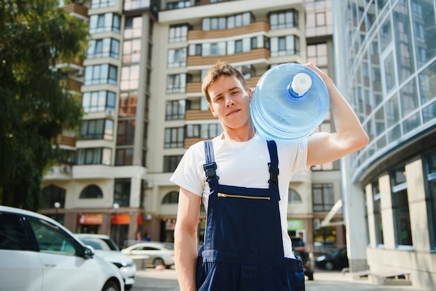 Smiling delivery man carrying water bottle on shoulder