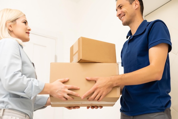 smiling delivery man giving boxes to woman customer at home for online shopping service concept