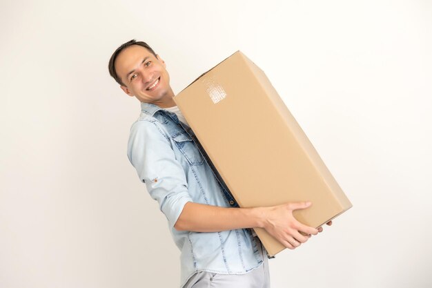 smiling delivery man holding a big parcel isolated on white