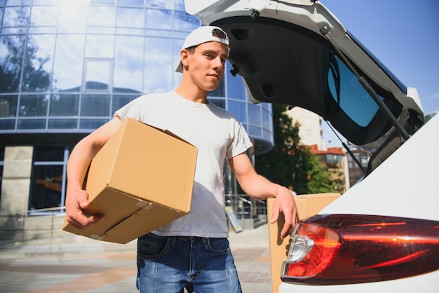 Photo smiling delivery man holding a paper box