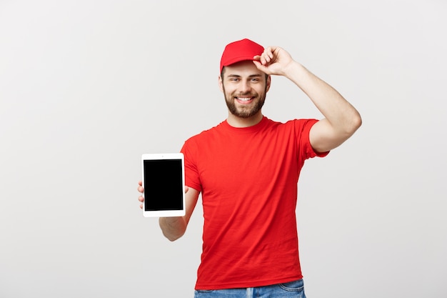smiling delivery man presenting tablet in his hand showing something.